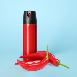 Bottle of pepper spray and red hot chilies on turquoise background