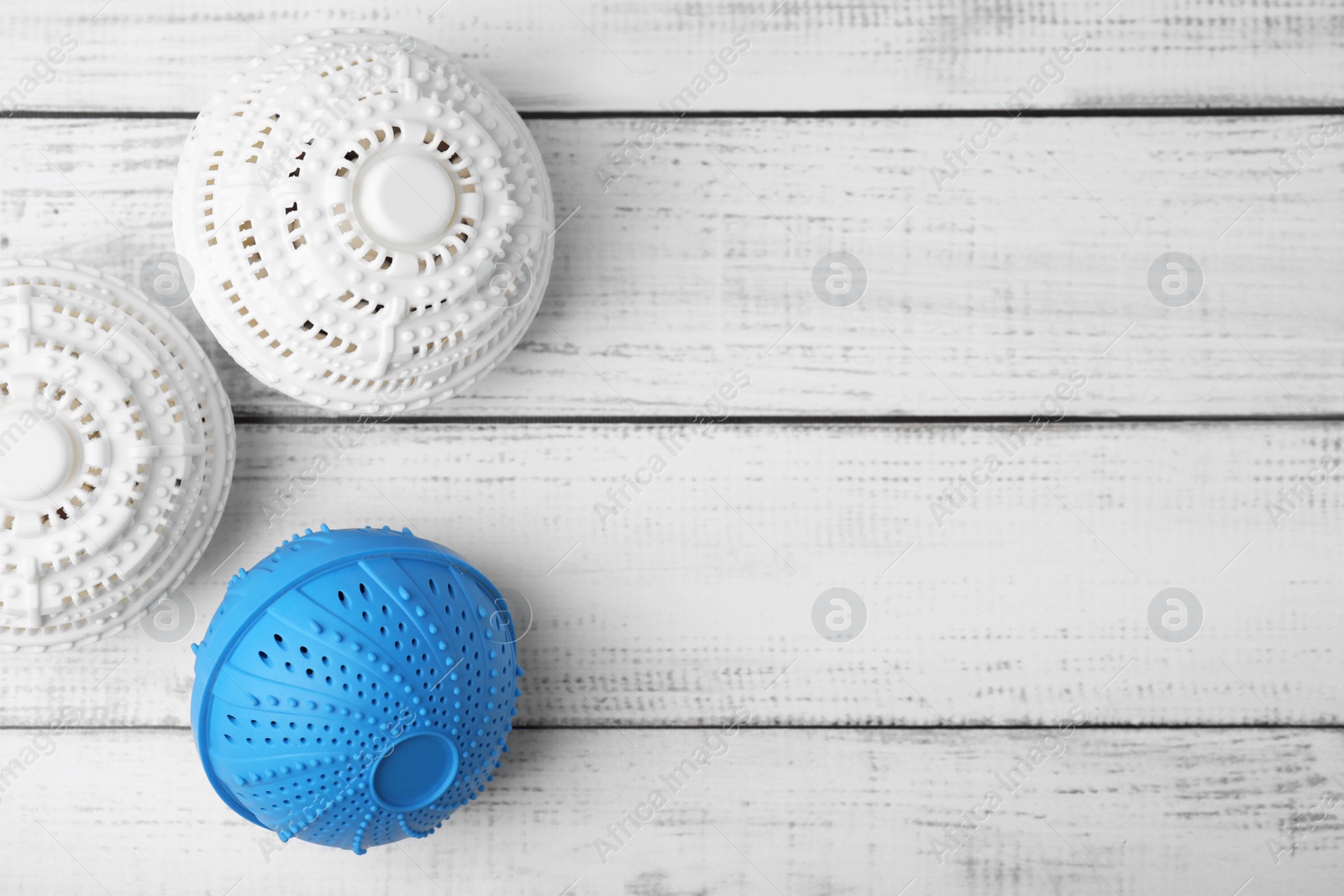 Photo of Laundry dryer balls on white wooden table., flat lay. Space for text