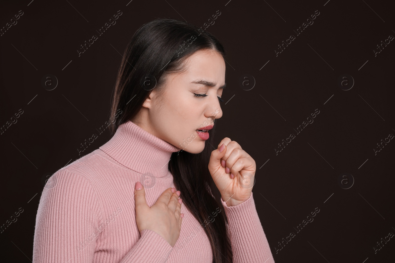 Photo of Young woman coughing on dark background. Cold symptoms