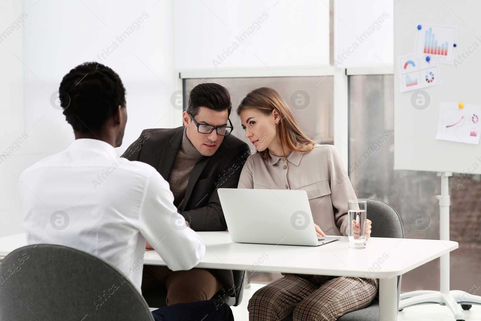 Photo of Coworkers conducting job interview with African American man in office. Racism concept