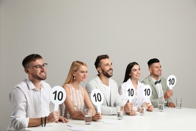 Photo of Panel of judges holding signs with highest score at table on beige background