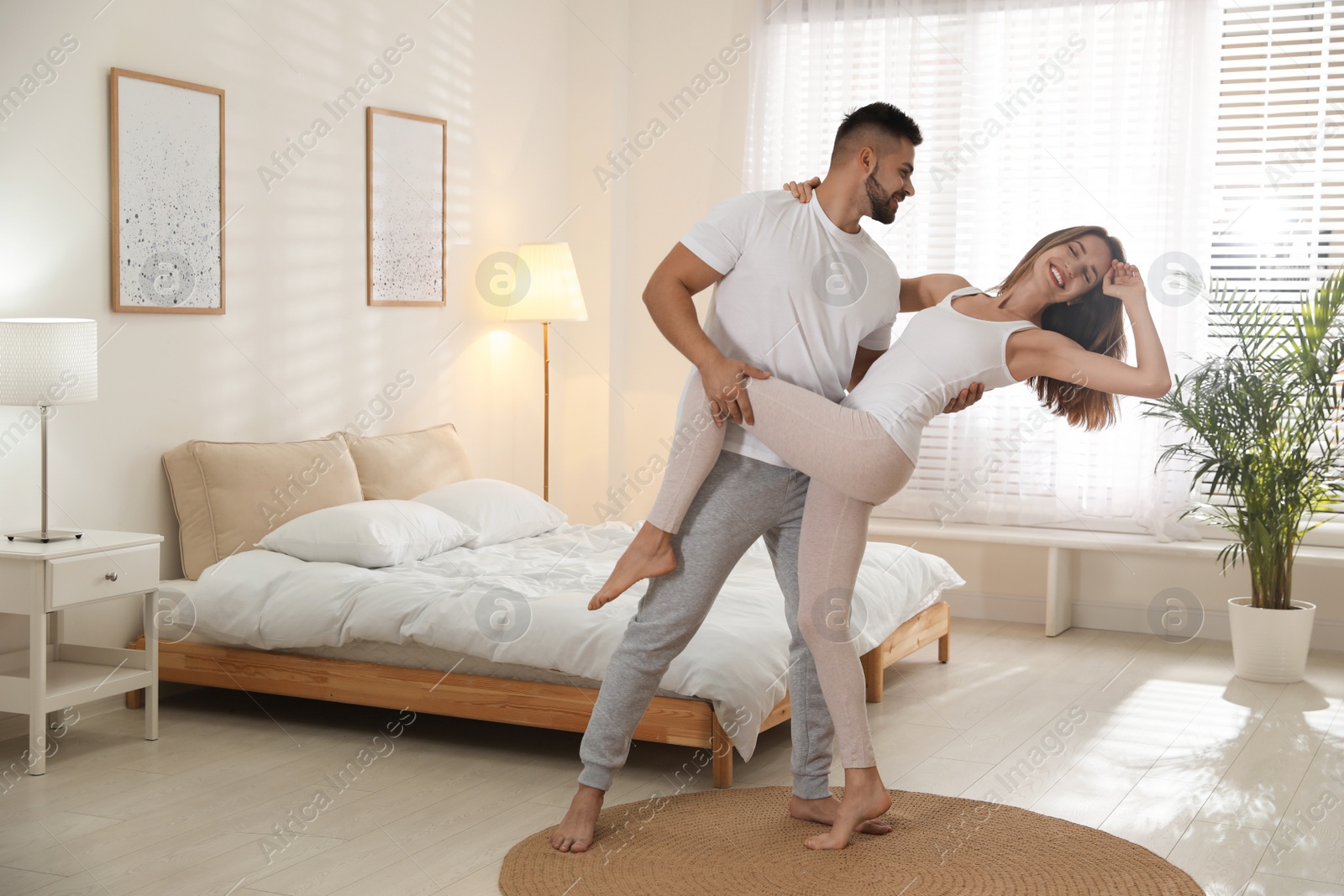 Photo of Lovely young couple dancing in bedroom at home