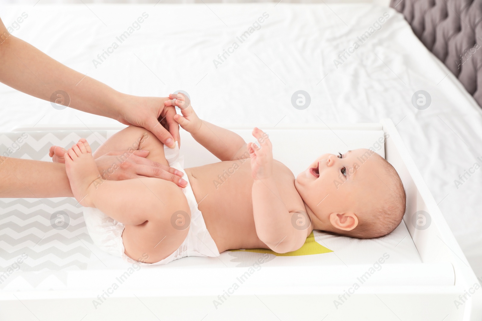 Photo of Mother changing her baby's diaper on table indoors