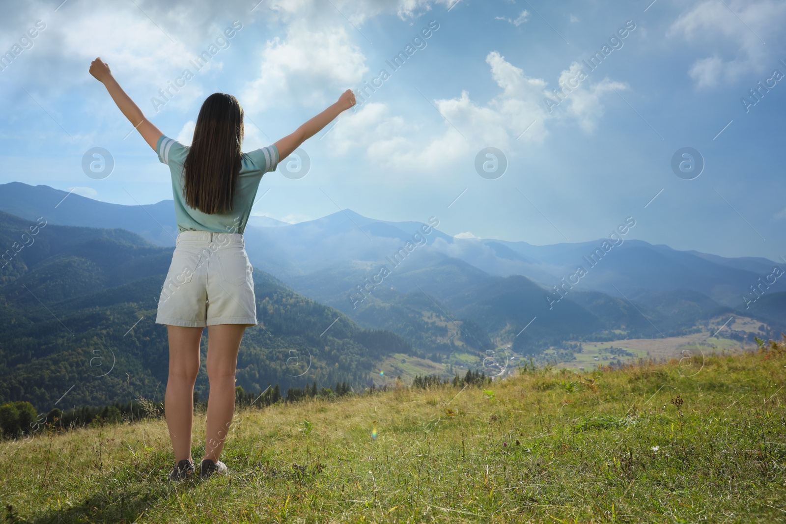 Photo of Tourist in mountains on sunny day, back view