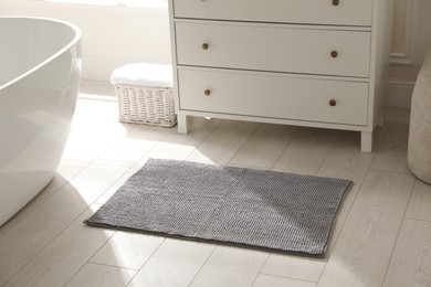 Photo of Stylish grey mat near chest of drawers in bathroom