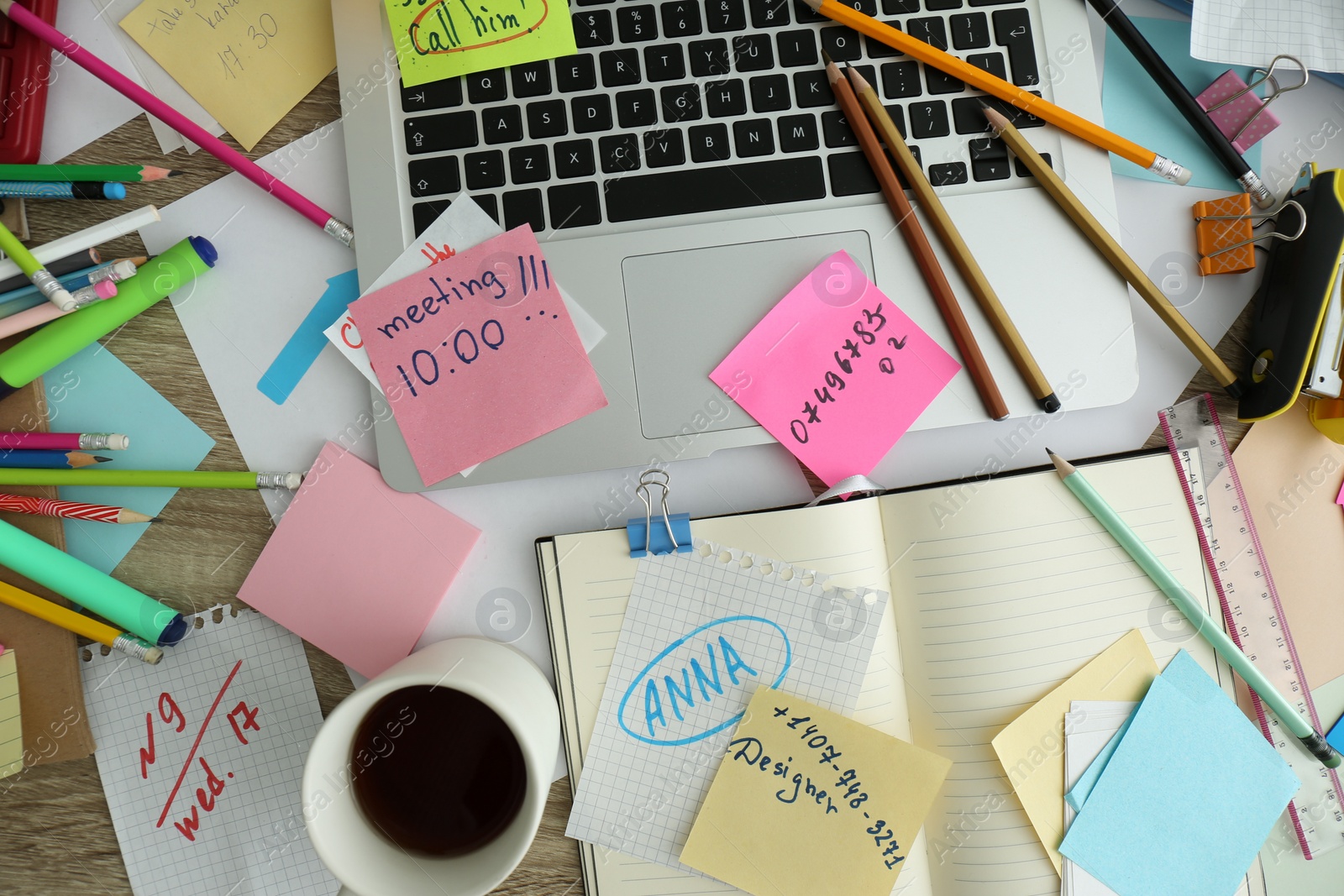 Photo of Laptop, notes and office stationery in mess on desk, top view. Overwhelmed with work