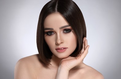 Portrait of pretty young woman with brown hair on grey background