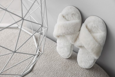 Photo of Soft fluffy white slippers near grey wall