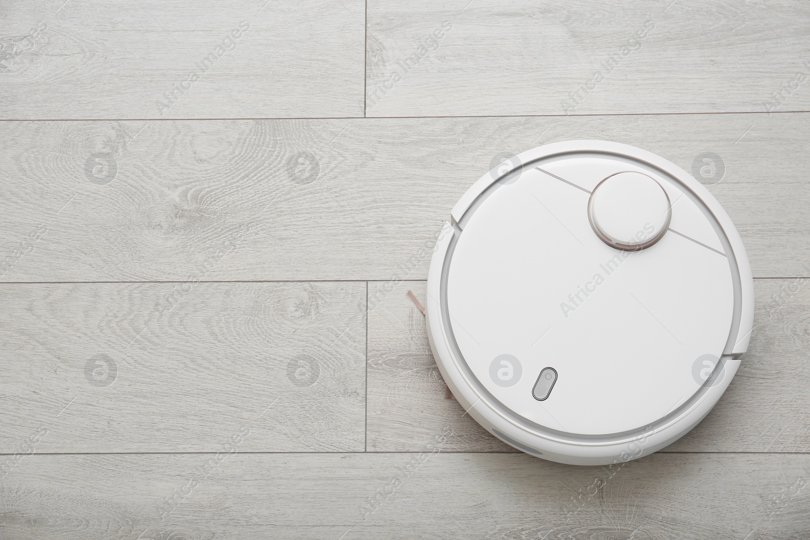 Photo of Modern robotic vacuum cleaner on wooden floor, top view. Space for text