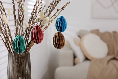 Photo of Beautiful pussy willow branches with paper eggs in vase at home, closeup and space for text. Easter decor