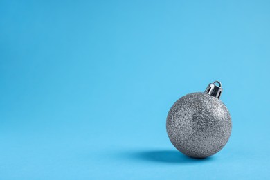 Photo of One glitter Christmas ball on light blue background. Space for text