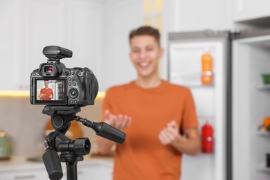 Photo of Food blogger recording video in kitchen, focus on camera