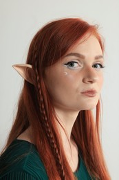 Photo of Beautiful redhead elf girl on light background