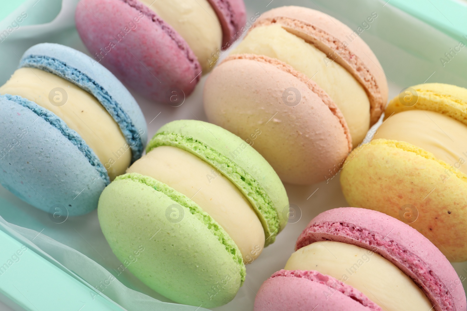 Photo of Many delicious colorful macarons in box, closeup