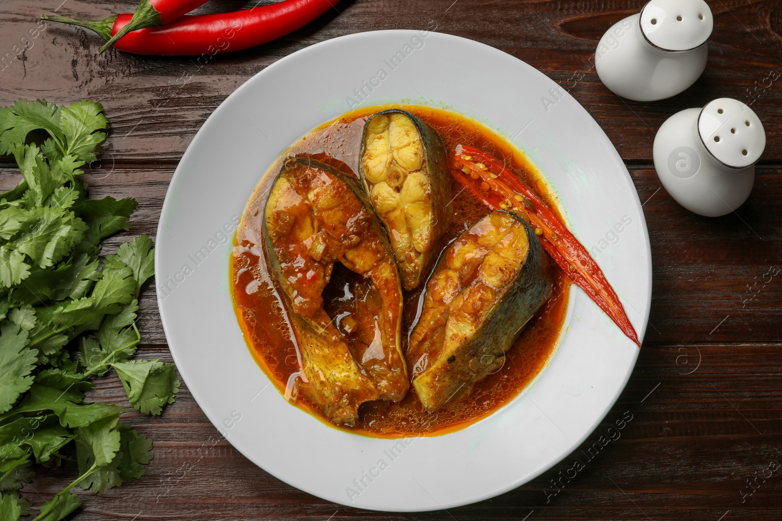 Photo of Tasty fish curry served on wooden table, flat lay. Indian cuisine