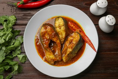 Tasty fish curry served on wooden table, flat lay. Indian cuisine