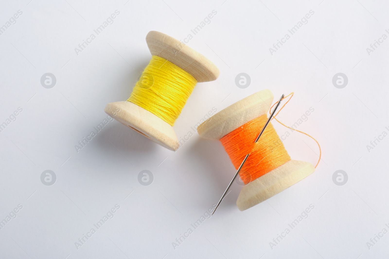 Photo of Colorful sewing threads with needle on white background, top view