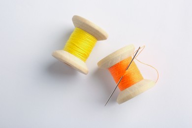 Photo of Colorful sewing threads with needle on white background, top view