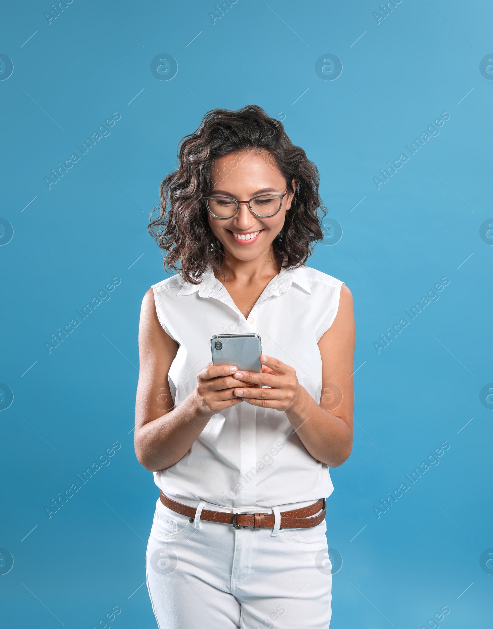 Photo of Happy young woman using smartphone on blue background