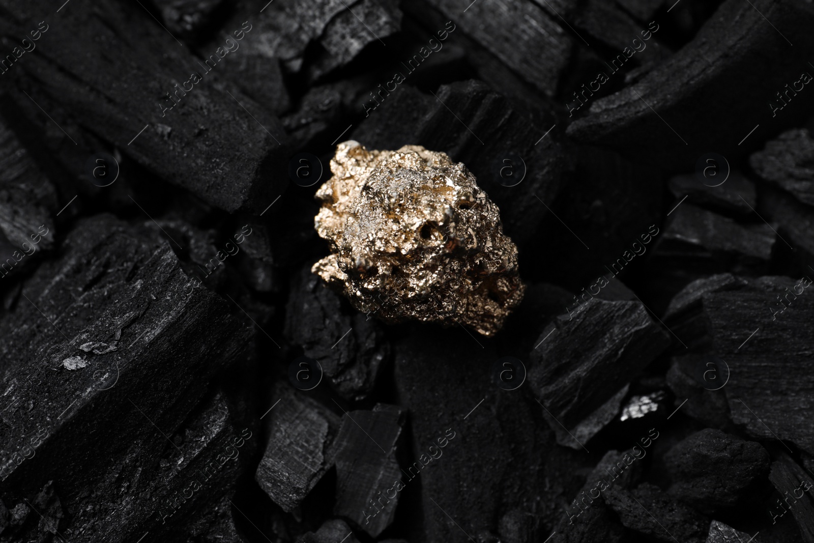 Photo of Shiny gold nugget on coals, top view