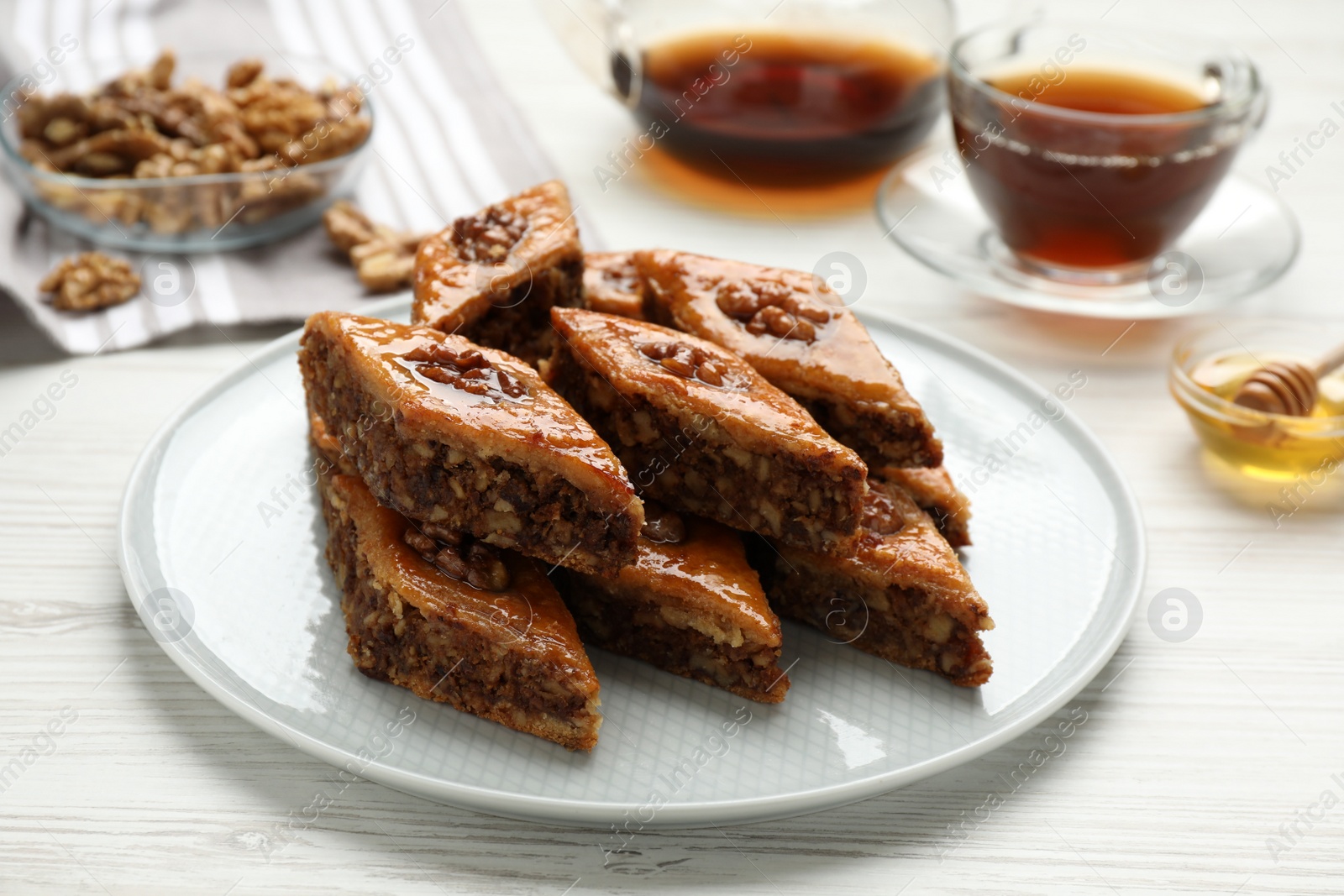 Photo of Delicious sweet baklava with walnuts on white wooden table, closeup