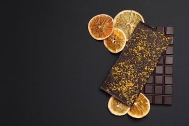 Photo of Chocolate bars with freeze dried orange on black background, flat lay. Space for text