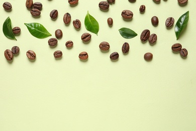 Photo of Fresh green coffee leaves and beans on light green background, flat lay. Space for text