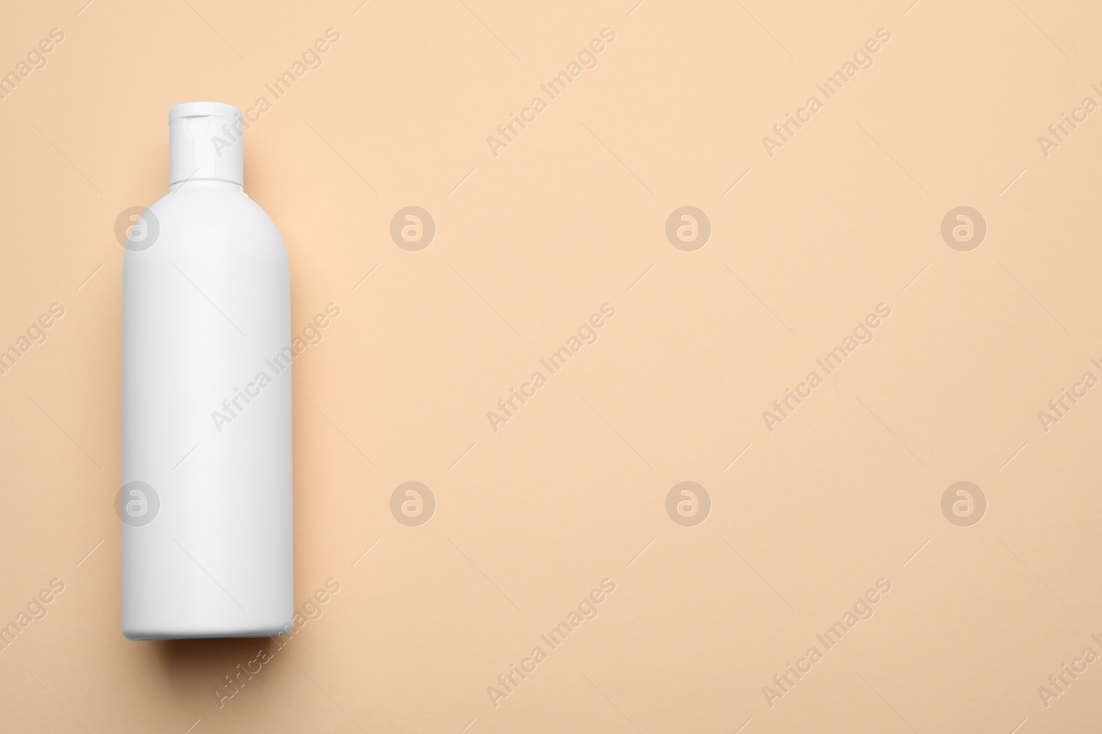 Photo of Bottle of shampoo on beige background, top view. Space for text