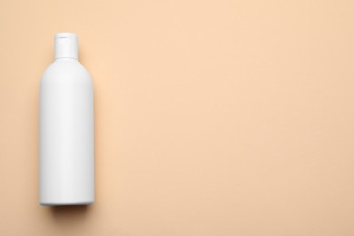 Photo of Bottle of shampoo on beige background, top view. Space for text