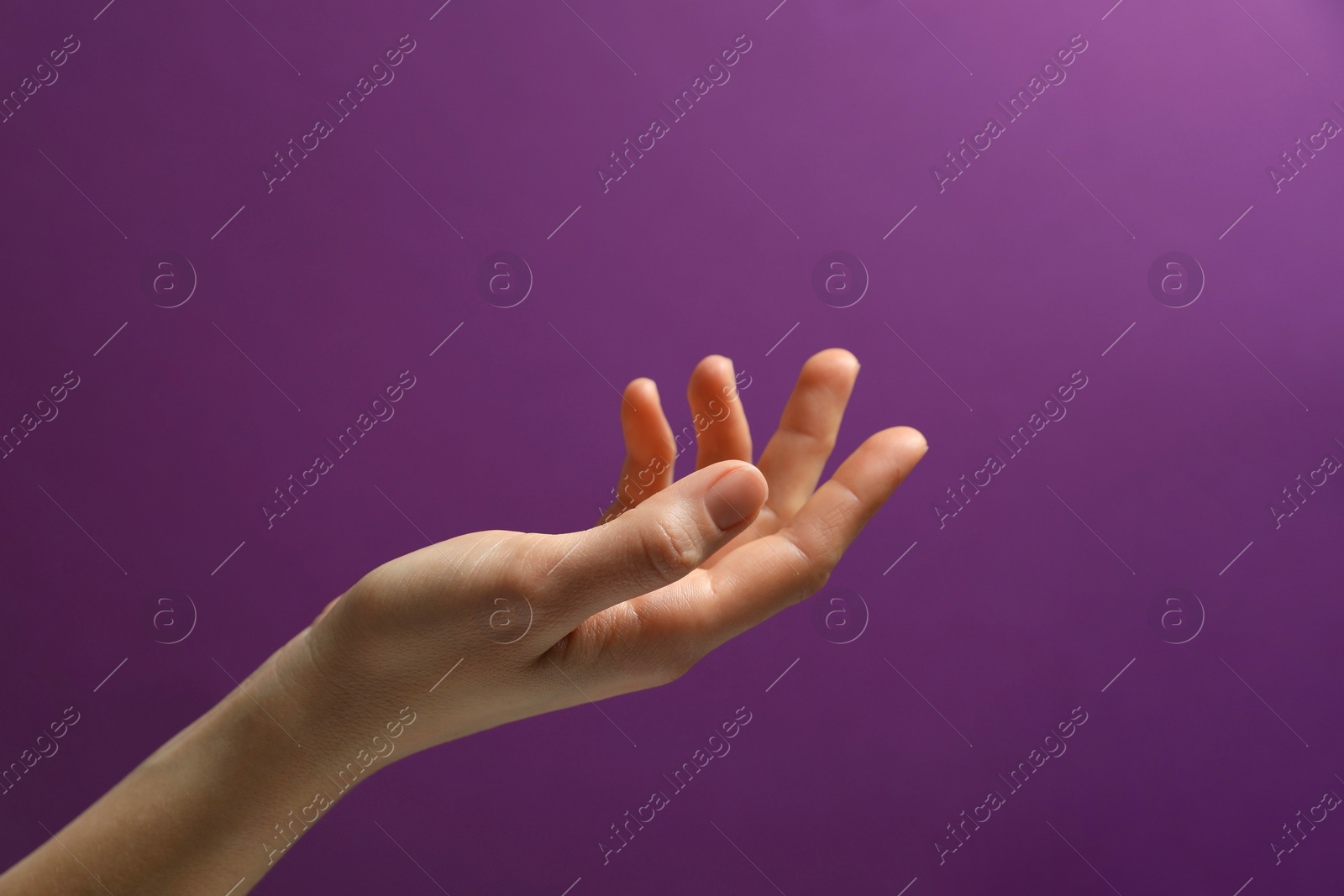 Photo of Woman holding something in hand on purple background, closeup