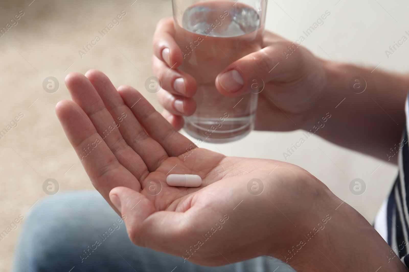 Photo of Man with glass of water and pill on blurred background, closeup