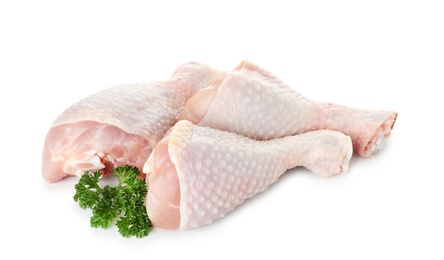 Photo of Raw chicken drumsticks with parsley on white background. Fresh meat