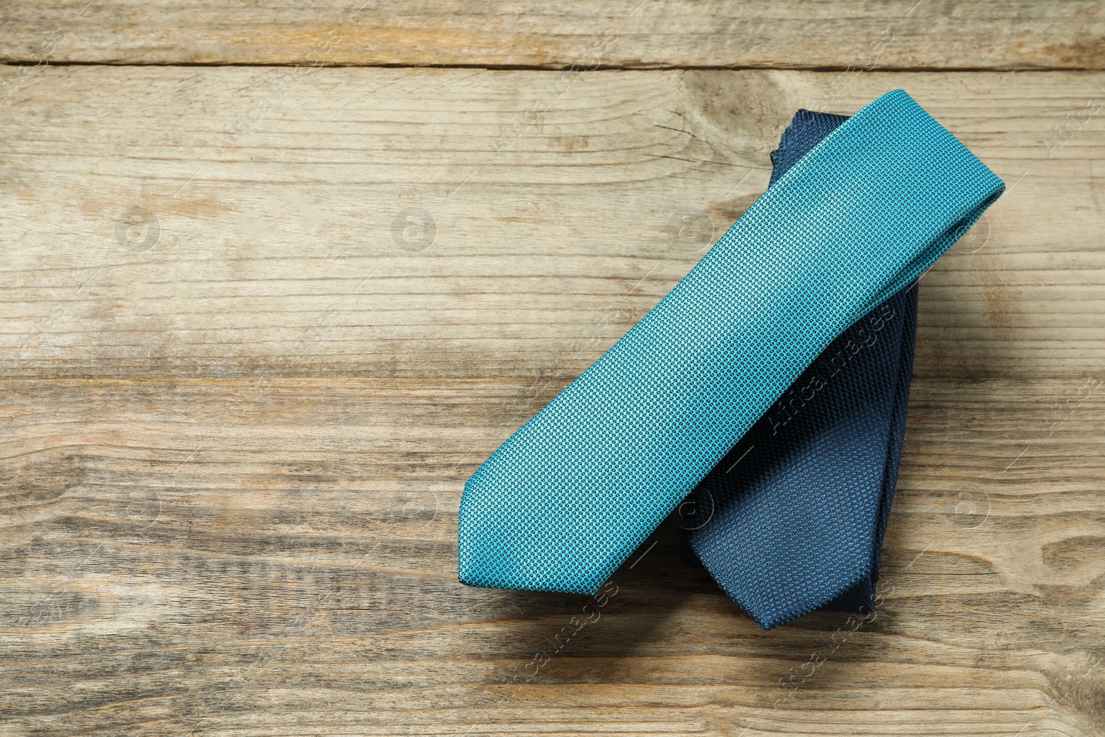 Photo of Two neckties on wooden table, top view. Space for text