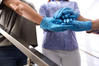 Photo of People in blue medical gloves stacking hands on blurred background, closeup