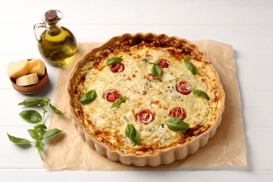 Photo of Delicious homemade cheese quiche and ingredients on white table