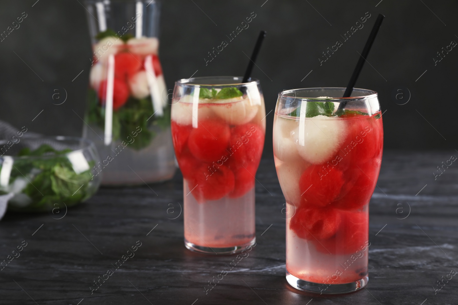 Photo of Glasses with tasty melon and watermelon ball drinks on dark table