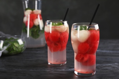 Glasses with tasty melon and watermelon ball drinks on dark table