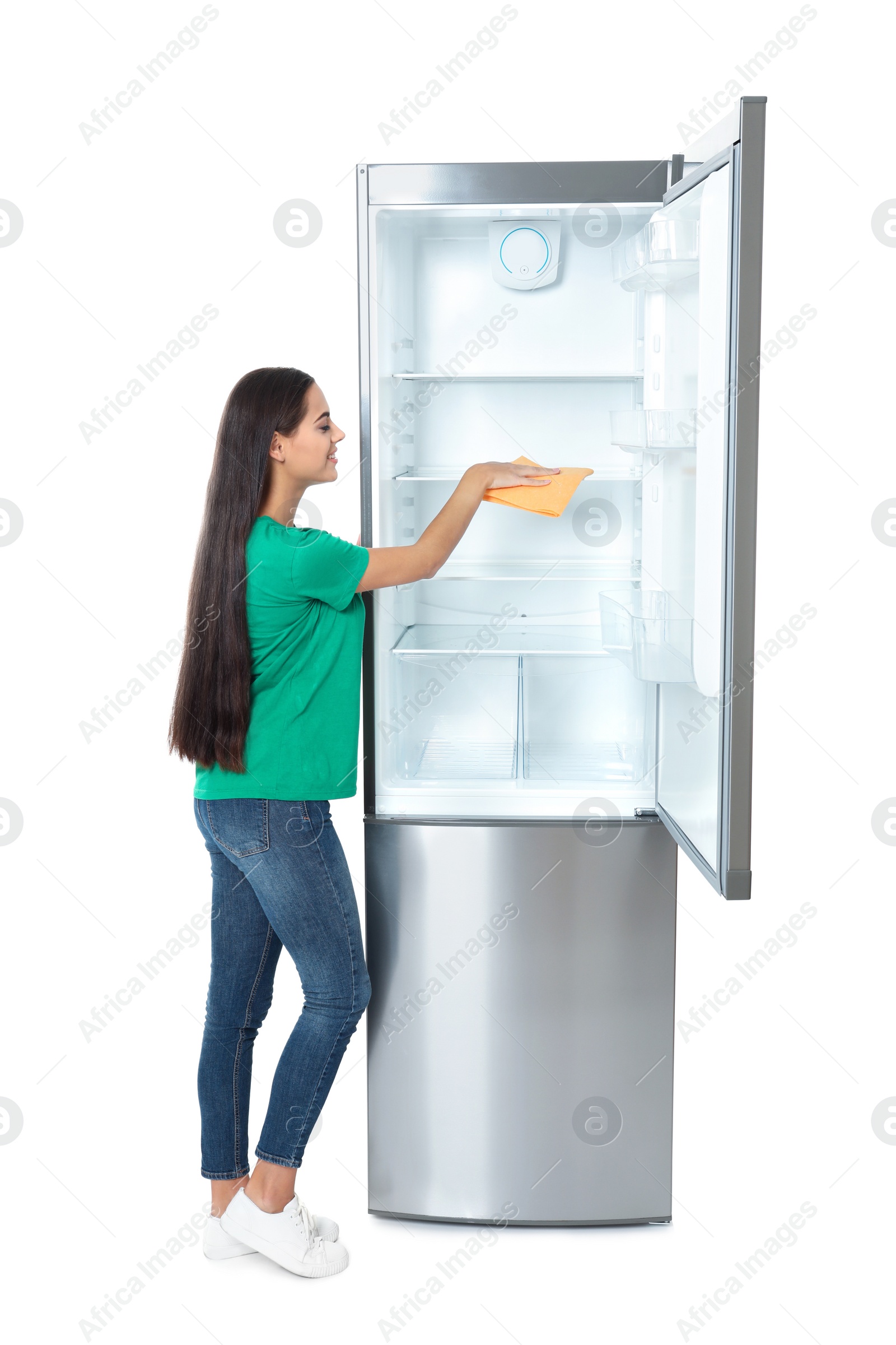 Photo of Young woman cleaning refrigerator with rag on white background