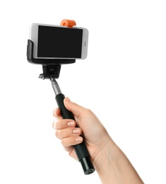 Woman holding selfie stick with mobile phone on white background