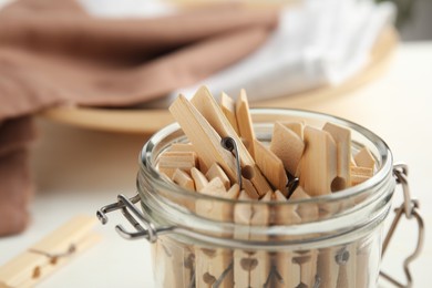 Many wooden clothespins in glass jar, closeup