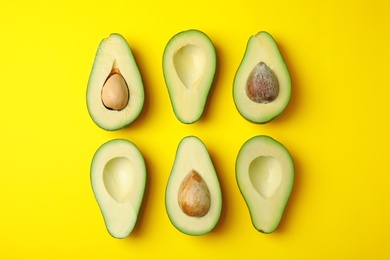 Cut fresh ripe avocados on yellow background, flat lay