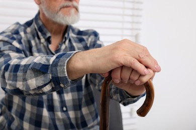 Senior man with walking cane at home, closeup