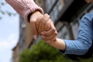 Little child holding hands with his mother outdoors, closeup. Family time