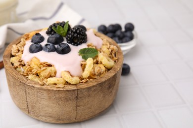 Tasty granola, yogurt and fresh berries in bowl on white tiled table, closeup with space for text. Healthy breakfast