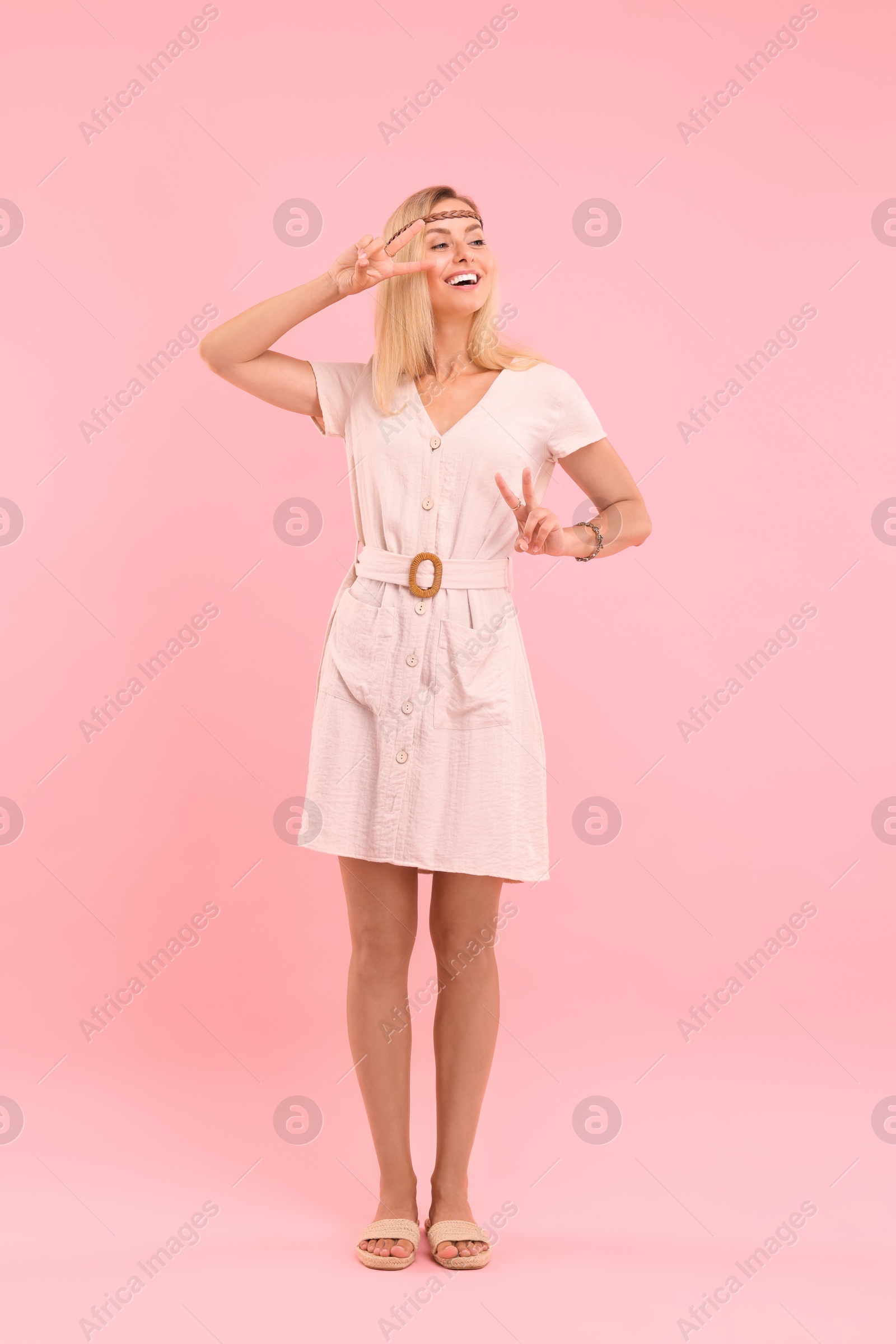 Photo of Beautiful hippie woman showing peace signs on pink background