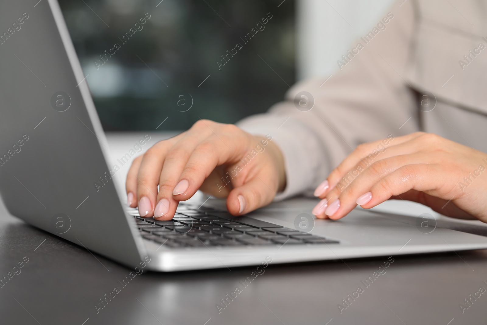 Photo of Woman working on laptop at table, closeup. Electronic document management