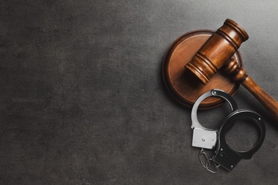 Judge's gavel and handcuffs on grey background, flat lay with space for text. Criminal law concept