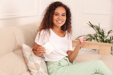 Young African American woman with menstrual cup and pad at home