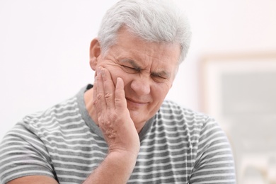 Photo of Mature man suffering from toothache at home