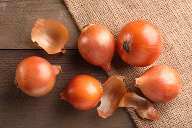 Photo of Many ripe onions on wooden table, flat lay